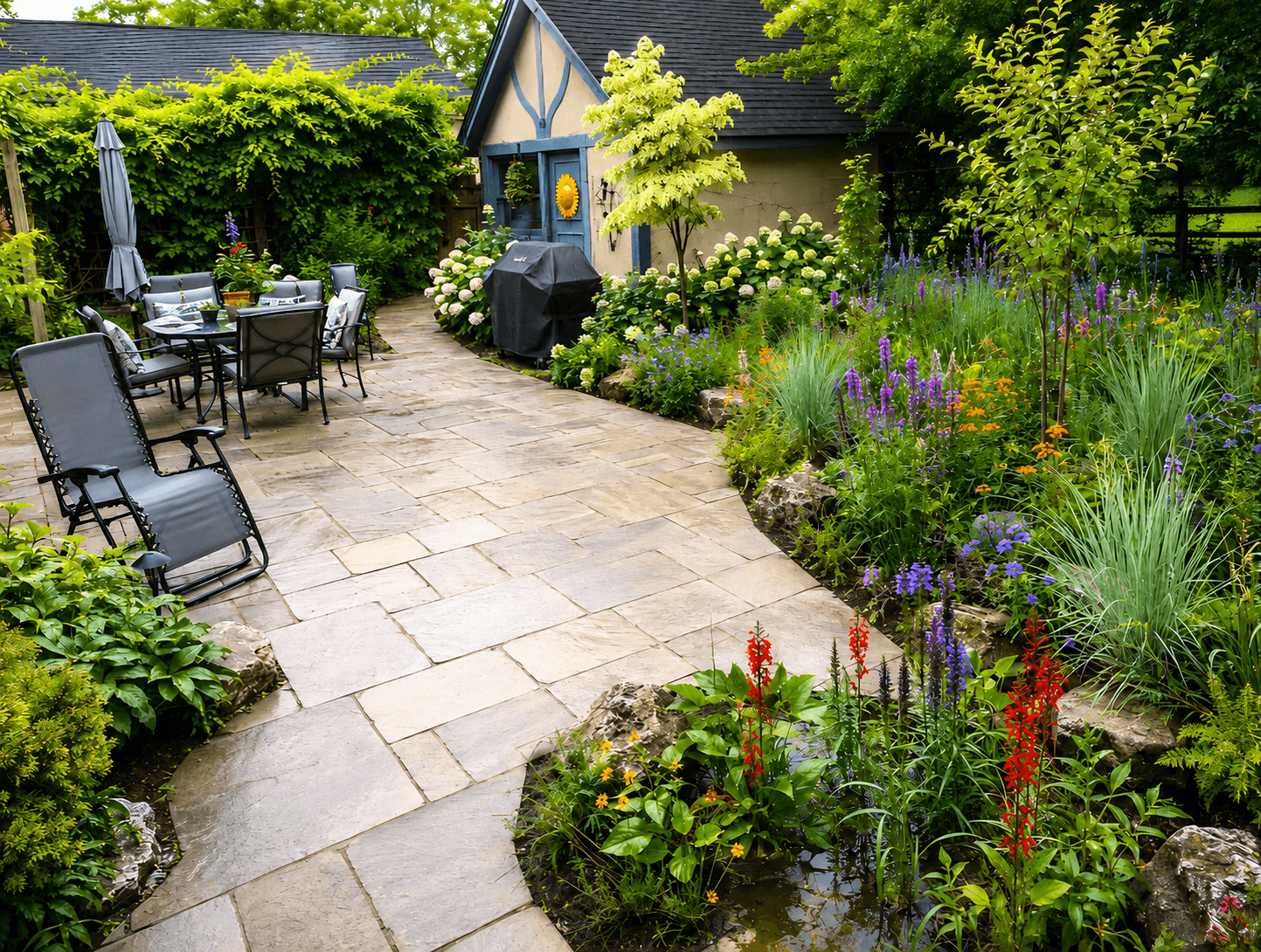 A stonework patio bordered by a native plant garden